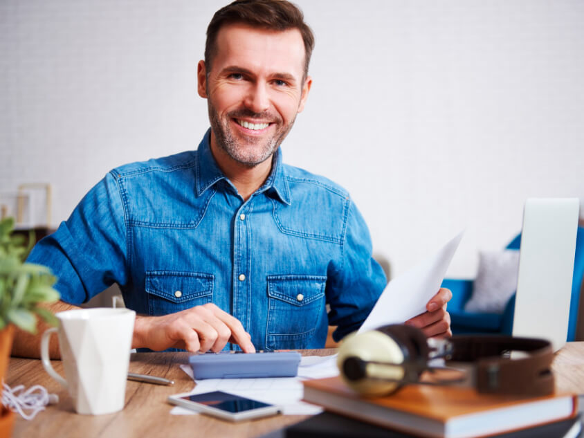 portrait smiling man calculating his monthly expenses
